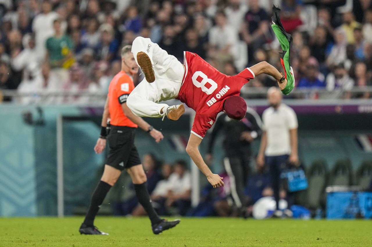 A pitch invader runs across the field during the World Cup group D soccer match between Tunisia and...