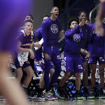 
              Hansel Enmanuel, center, a freshman guard from the Dominican Republic for Northwestern State, cheers a score with his teammates from the bench during an NCAA college basketball game against Rice Saturday, Dec. 17, 2022, in Houston. Enmanuel lost his left arm in a childhood accident and has attained the talent and skill to play at the college level. (AP Photo/Michael Wyke)
            