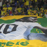 
              Brazilian fans hold a banner showing the Brazilian soccer legend Pele with the message 'Get well soon' during the World Cup round of 16 soccer match between Brazil and South Korea at the Stadium 974 in Doha, Qatar, Monday, Dec. 5, 2022. Pele is in a hospital in San Paulo recovering from a respiratory infection. (AP Photo/Jin-Man Lee)
            