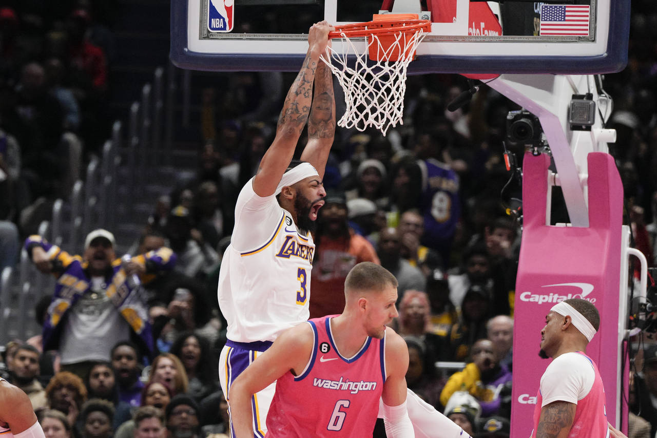 Los Angeles Lakers forward Anthony Davis, left, dunks against Washington Wizards centers Daniel Gaf...
