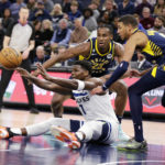 
              Minnesota Timberwolves guard Anthony Edwards (1) passes under pressure from Indiana Pacers forward Aaron Nesmith (23) and guard Tyrese Haliburton (0) during the second quarter of an NBA basketball game Wednesday, Dec. 7, 2022, in Minneapolis. (AP Photo/Andy Clayton-King)
            