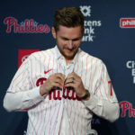 
              Newly acquired Philadelphia Phillies shortstop Trea Turner puts on a jersey during his introductory news conference, Thursday, Dec. 8, 2022, in Philadelphia. (AP Photo/Matt Slocum)
            