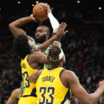 
              Boston Celtics guard Jaylen Brown looks to pass while covered by Indiana Pacers forward Aaron Nesmith (23) and center Myles Turner (33) during the first half of an NBA basketball game Wednesday, Dec. 21, 2022, in Boston. (AP Photo/Charles Krupa)
            