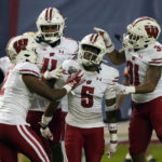 
              Wisconsin cornerback Cedrick Dort Jr. celebrates with Ricardo Hallman (2), Alexander Smith (11), and Amaun Williams (31) after intercepting the football against Oklahoma State during the second half of the Guaranteed Rate Bowl NCAA college football game Tuesday, Dec. 27, 2022, in Phoenix. Wisconsin 24-17. (AP Photo/Rick Scuteri)
            