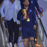 
              Argentina's Lionel Messi holds the FIFA World Cup trophy as he deplanes in Buenos Aires, Argentina, early Tuesday, Dec. 20, 2022. (AP Photo/Gustavo Garello)
            