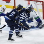 
              Vancouver Canucks goaltender Collin Delia (60) saves against a shot by Winnipeg Jets' Kevin Stenlund (28) as Canucks' Luke Schenn (2) defends during second-period NHL hockey game action in Winnipeg, Manitoba, Thursday, Dec. 29, 2022. (John Woods/The Canadian Press via AP)
            