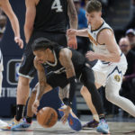 
              Memphis Grizzlies guard Ja Morant, left, collects a loose ball as Denver Nuggets guard Christian Braun defends in the first half of an NBA basketball game Tuesday, Dec. 20, 2022, in Denver. (AP Photo/David Zalubowski)
            