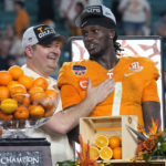 
              Tennessee coach Josh Heupel, left, and quarterback Joe Milton III (7) stand behind the trophy after the team's win over Clemson in the Orange Bowl NCAA college football game Saturday, Dec. 31, 2022, in Miami Gardens, Fla. (AP Photo/Lynne Sladky
            