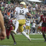 
              Notre Dame quarterback Tyler Buchner (12) crosses into the end zone for a touchdown during the first quarter of the Gator Bowl NCAA college football game against South Carolina on Friday, Dec. 30, 2022, in Jacksonville, Fla. (AP Photo/Gary McCullough)
            