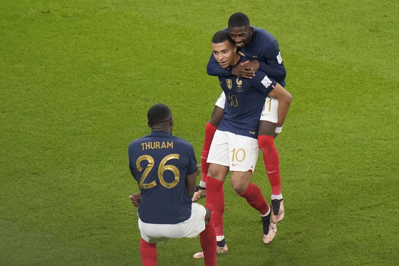 France's Kylian Mbappe, center, celebrates after scoring with teammate France's Ousmane Dembele, to...