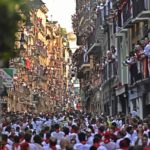 
              People run through the streets ahead of fighting bulls and steers during the first day of the running of the bulls at the San Fermin Festival in Pamplona, northern Spain, Thursday, July 7, 2022. Revelers from around the world flock to Pamplona every year for nine days of uninterrupted partying in Pamplona's famed running of the bulls festival which was suspended for the past two years because of the coronavirus pandemic. (AP Photo/Alvaro Barrientos)
            