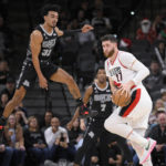 
              Portland Trail Blazers' Jusuf Nurkic (27) looks to pass as he is defended by San Antonio Spurs' Tre Jones during the second half of an NBA basketball game, Wednesday, Dec. 14, 2022, in San Antonio. Portland won 128-112. (AP Photo/Darren Abate)
            