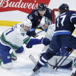 
              Vancouver Canucks goaltender Collin Delia (60) saves against a shot by Winnipeg Jets' Adam Lowry (17) as Canucks' Tyler Myers (57) defends during second-period NHL hockey game action in Winnipeg, Manitoba, Thursday, Dec. 29, 2022. (John Woods/The Canadian Press via AP)
            