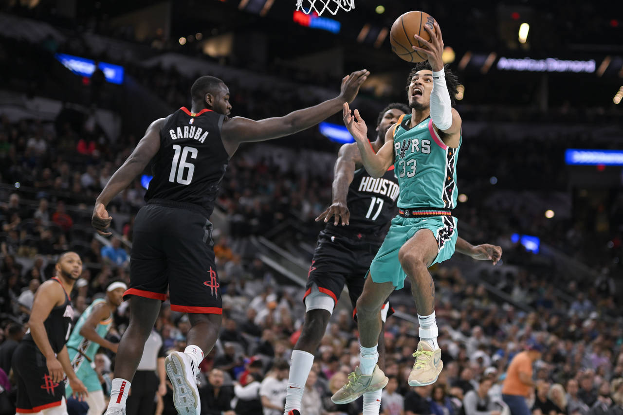 San Antonio Spurs' Tre Jones (33) goes to the basket against Houston Rockets' Usman Garuba (16) and...
