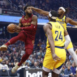 
              Cleveland Cavaliers guard Donovan Mitchell (45) passes against Indiana Pacers guard Buddy Hield (24) and center Myles Turner (33) during the first half of an NBA basketball game, Friday, Dec. 16, 2022, in Cleveland. (AP Photo/Ron Schwane)
            