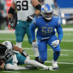 
              Jacksonville Jaguars quarterback Trevor Lawrence holds his left leg after being sacked by Detroit Lions linebacker James Houston (59) during the first half of an NFL football game, Sunday, Dec. 4, 2022, in Detroit. (AP Photo/Paul Sancya)
            