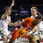 
              Syracuse's Judah Mintz (3) tries to get around as Notre Dame's Dane Goodwin, right, and Cormac Ryan, left, defend during the first half of an NCAA college basketball game on Saturday, Dec. 3, 2022 in South Bend, Ind. (AP Photo/Michael Caterina)
            