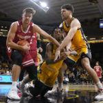 
              Wisconsin forward Carter Gilmore, left, fights for a rebound with Iowa guard Dasonte Bowen, center, and forward Filip Rebraca, right, during the first half of an NCAA college basketball game, Sunday, Dec. 11, 2022, in Iowa City, Iowa. (AP Photo/Charlie Neibergall)
            
