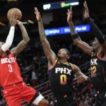 
              Houston Rockets guard Kevin Porter Jr. (3) shoots as Phoenix Suns forward Torrey Craig (0) and center Deandre Ayton defend during the first half of an NBA basketball game, Tuesday, Dec. 13, 2022, in Houston. (AP Photo/Eric Christian Smith)
            