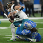 
              Jacksonville Jaguars quarterback Trevor Lawrence (16) is sacked by Detroit Lions linebacker James Houston (59) during the first half of an NFL football game, Sunday, Dec. 4, 2022, in Detroit. (AP Photo/Paul Sancya)
            