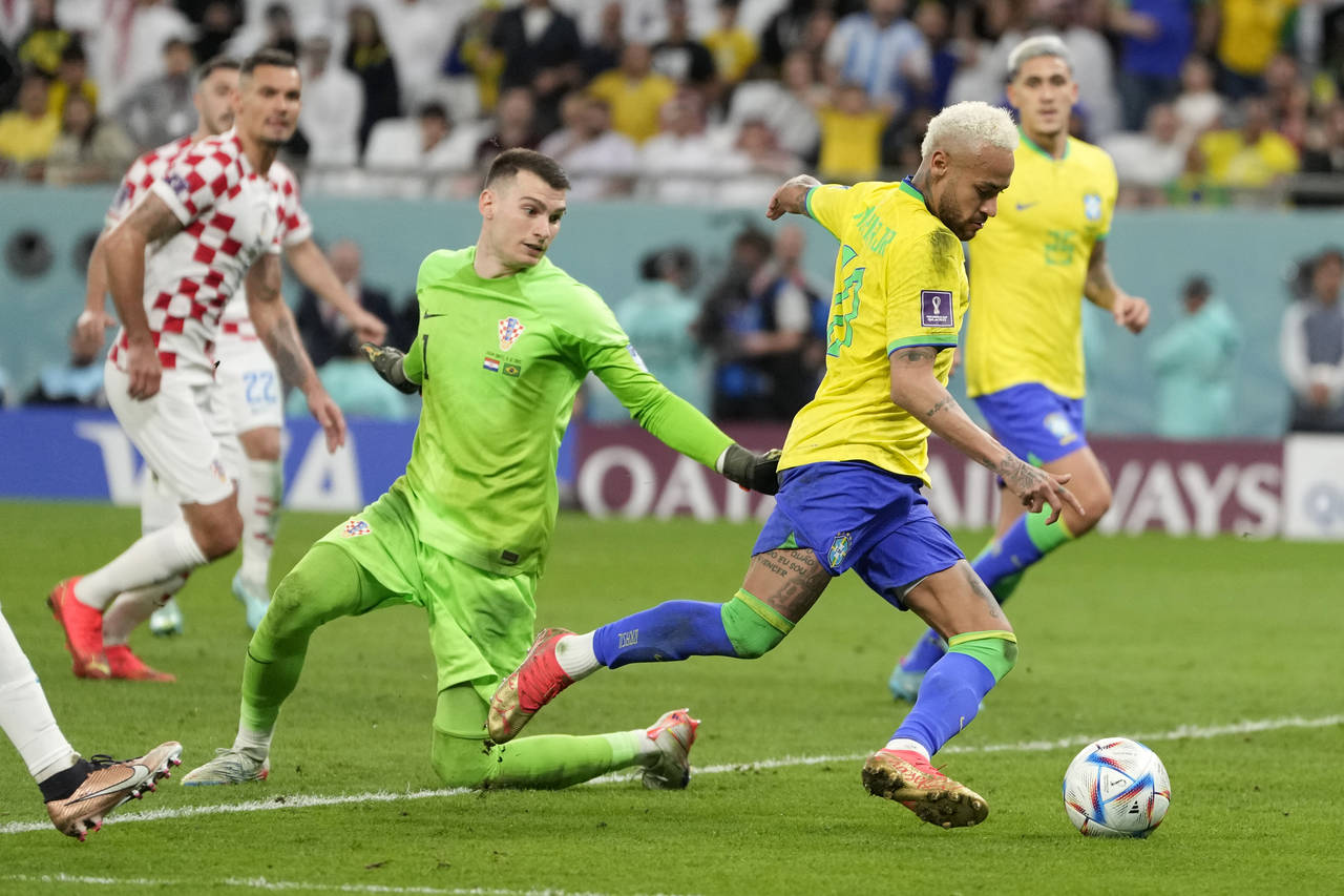 FILE - Brazil's Neymar takes the ball past Croatia's goalkeeper Dominik Livakovic on his way to sco...