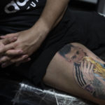 
              Sebastian Fernandez rests as artist César "Yeyo" Molina tattoos his leg with an image of soccer player Lionel Messi kissing the World Cup trophy, in Buenos Aires, Argentina, Thursday, Dec. 29, 2022. (AP Photo/Victor R. Caivano)
            
