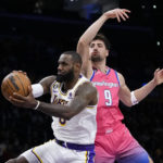 
              Los Angeles Lakers' LeBron James, left, gets a rebound against Washington Wizards' Deni Avdija (9) during first half of an NBA basketball game Sunday, Dec. 18, 2022, in Los Angeles. (AP Photo/Jae C. Hong)
            