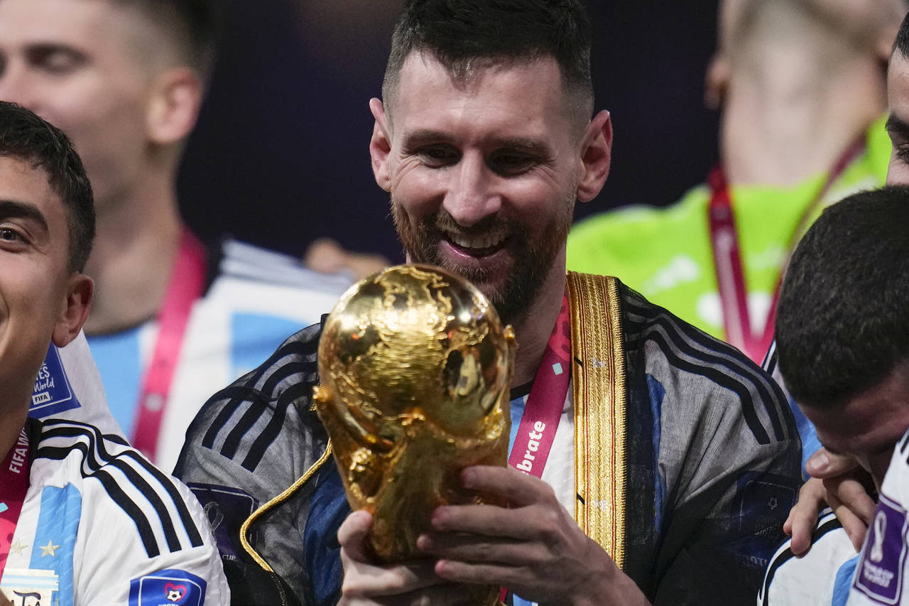 Argentina's Lionel Messi holds the trophy after winning the World Cup final soccer match between Ar...
