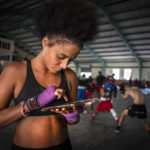
              Boxer Giselle Bello Garcia texts on a mobile phone while other athletes train at a boxing gym in Havana, Cuba, Monday, Dec. 5, 2022. Cuban officials announced on Monday that women boxers would be able to compete for the first time ever. (AP Photo/Ramon Espinosa)
            