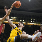 
              Iowa forward Filip Rebraca (0) fights for a rebound with Wisconsin forward Carter Gilmore, left, and guard Chucky Hepburn, right, during the first half of an NCAA college basketball game, Sunday, Dec. 11, 2022, in Iowa City, Iowa. (AP Photo/Charlie Neibergall)
            