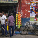 
              People buy grocery from a shop next to a garlanded photograph of Portugal's Cristiano Ronaldo put up by fans to mark the ongoing soccer World Cup in Kolkata, India, Thursday, Dec. 8, 2022. (AP Photo/Bikas Das)
            