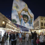 
              A fan of Argentina waves a flag with the image of late Argentinean soccer star Diego Maradona in Souq Waqif market in Doha, Qatar, Thursday, Dec. 15, 2022. Argentina will face France in the World Cup final match on Dec. 18. (AP Photo/Andre Penner)
            
