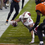 
              Wisconsin wide receiver Chimere Dike dives for the end zone in front of Oklahoma State cornerback Korie Black (2) during the first half of the Guaranteed Rate Bowl NCAA college football game Tuesday, Dec. 27, 2022, in Phoenix. (AP Photo/Rick Scuteri)
            