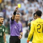 
              Referee Slavko Vincic of Slovenia, centre, show a yellow card to Saudi Arabia's goalkeeper Mohammed Al-Owais during the World Cup group C soccer match between Argentina and Saudi Arabia at the Lusail Stadium in Lusail, Qatar, Tuesday, Nov. 22, 2022. (AP Photo/Ebrahim Noroozi)
            