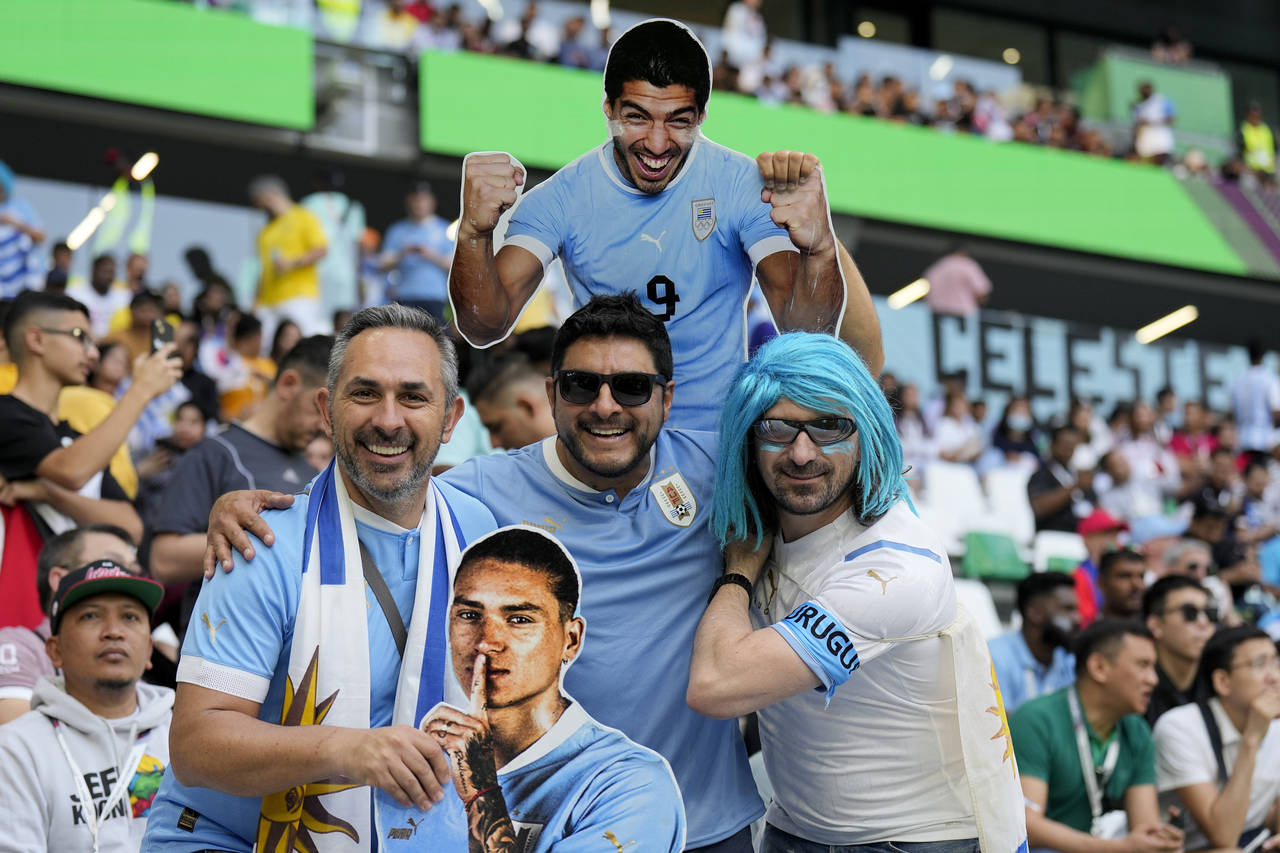 Uruguay soccer fans pose for a picture holding images of Uruguay's players Luis Suarez, above, and ...