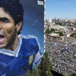 
              A mural of the late, soccer legend Diego Maradona stands tall as soccer fans walk to catch a glimpse of the open-top bus carrying the Argentine national soccer team that won the World Cup title during their homecoming parade in Buenos Aires, Argentina, Tuesday, Dec. 20, 2022. (AP Photo/Mario De Fina)
            