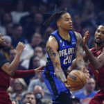 
              Orlando Magic guard Markelle Fultz (20) passes the ball from between Cleveland Cavaliers forward Evan Mobley (4) and guard Darius Garland (10) during the first half of an NBA basketball game Friday, Dec. 2, 2022, in Cleveland. (AP Photo/Ron Schwane)
            
