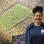 
              Michigan's Mimi Bolden-Morris, the first female graduate assistant football coach at Power Five school since the late 1980s, poses for a photo in front of a mural of Michigan Stadium, on Dec, 15, 2022, in Ann Arbor, Mich. (AP Photo/Larry Lage)
            