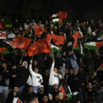 
              FILE - Palestinians wave Moroccan and Palestinian flags as they watch a live broadcast of the World Cup quarterfinal soccer match between Morocco and Portugal played in Qatar, in the West Bank town of Nablus, Saturday, Dec. 10, 2022. (AP Photo/Majdi Mohammed, File)
            
