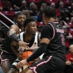 
              San Diego State guard Darrion Trammell center, looks to pass as Troy guard Aamer Muhammad (2) and guard Darius McNeill defend during the first half of an NCAA college basketball game Monday, Dec. 5, 2022, in San Diego. (AP Photo/Gregory Bull)
            