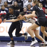 
              Providence's Janai Crooms, left, steals the ball from Connecticut's Caroline Ducharme, center, as Providence's Logan Cook (12) defends in the first half of an NCAA college basketball game, Friday, Dec. 2, 2022, in Storrs, Conn. (AP Photo/Jessica Hill)
            