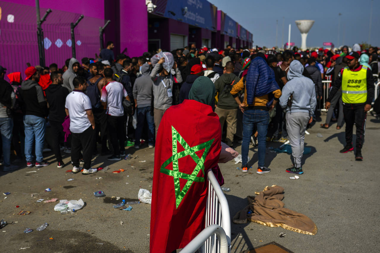 A man draped in a Moroccan flag queues with supporters outside the Al Janoub Stadium in Wakrah, Qat...