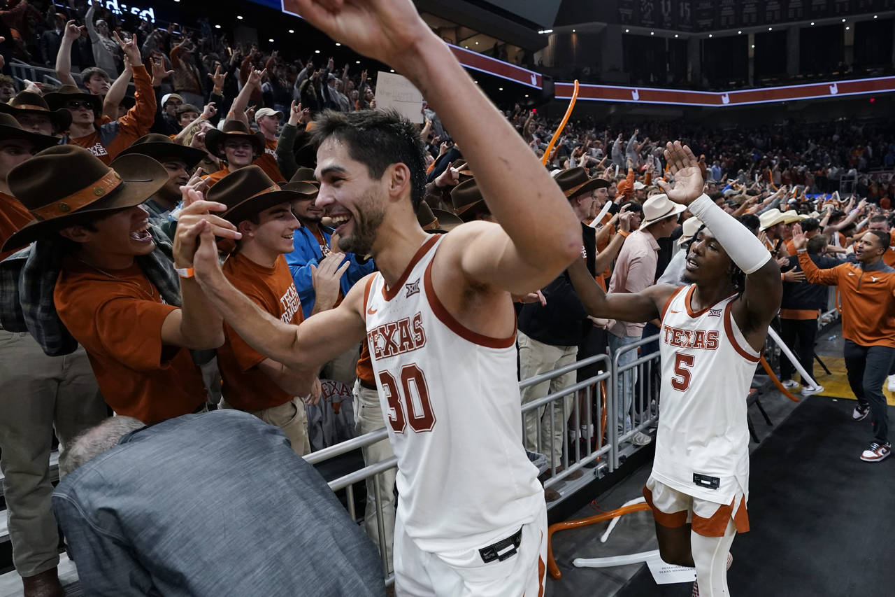 Texas forward Brock Cunningham (30) and guard Marcus Carr (5) celebrate with fans after the team's ...