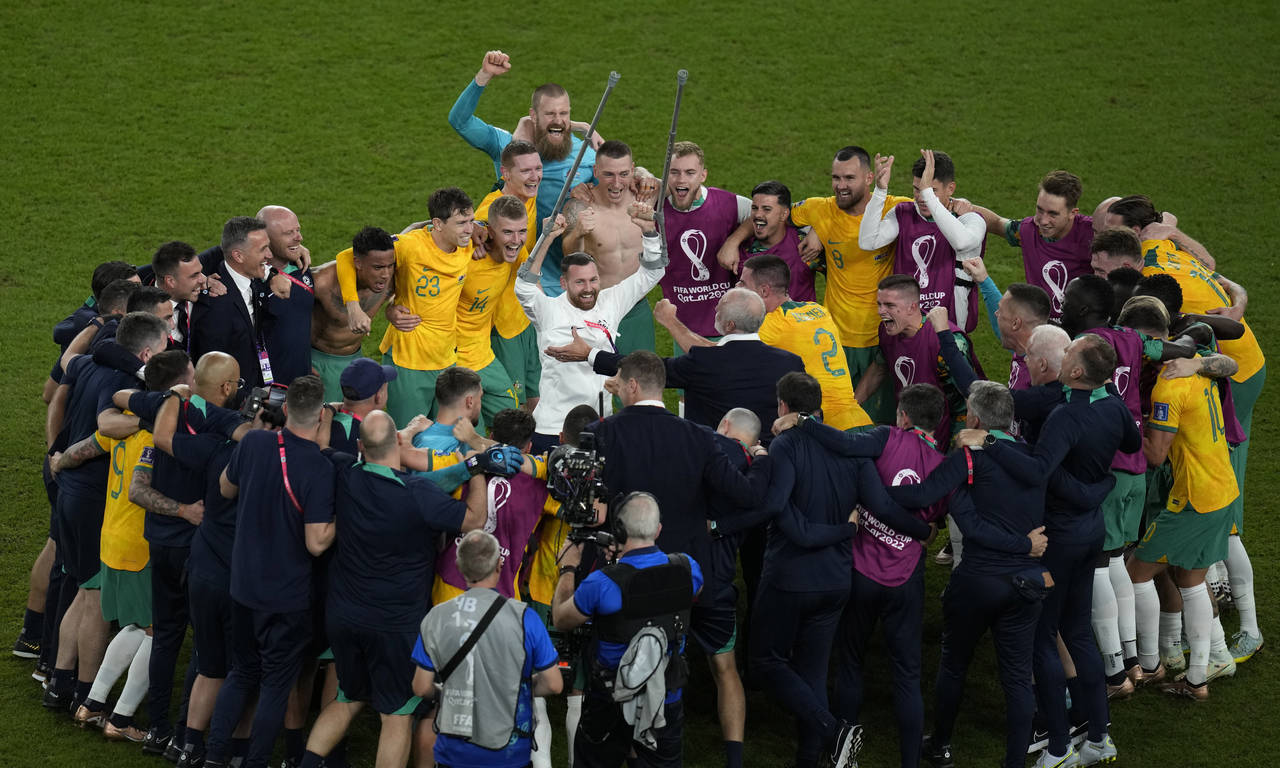 Australia's players celebrate their 1-0 victory at the end of the World Cup group D soccer match be...