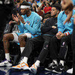 
              Phoenix Suns guard Devin Booker, wearing black, sits on the bench next to forward Torrey Craig in the first half of an NBA basketball game against the Denver Nuggets, Sunday, Dec. 25, 2022, in Denver. Booker, who was returning from an injury, played briefly in the first quarter before leaving the floor for the locker room and then returning to the bench. (AP Photo/David Zalubowski)
            