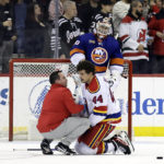 
              New Jersey Devils left wing Miles Wood is checked on by a team trainer during the second period of an NHL hockey game against the New York Islanders on Friday, Dec. 9, 2022, in Newark, N.J. (AP Photo/Adam Hunger)
            