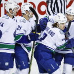 
              Vancouver Canucks forward Conor Garland (8) celebrates his goal with teammates during the first period of an NHL hockey game against the Calgary Flames in Calgary, Alberta on Wednesday, Dec. 14, 2022. (Jeff McIntosh/The Canadian Press via AP)
            