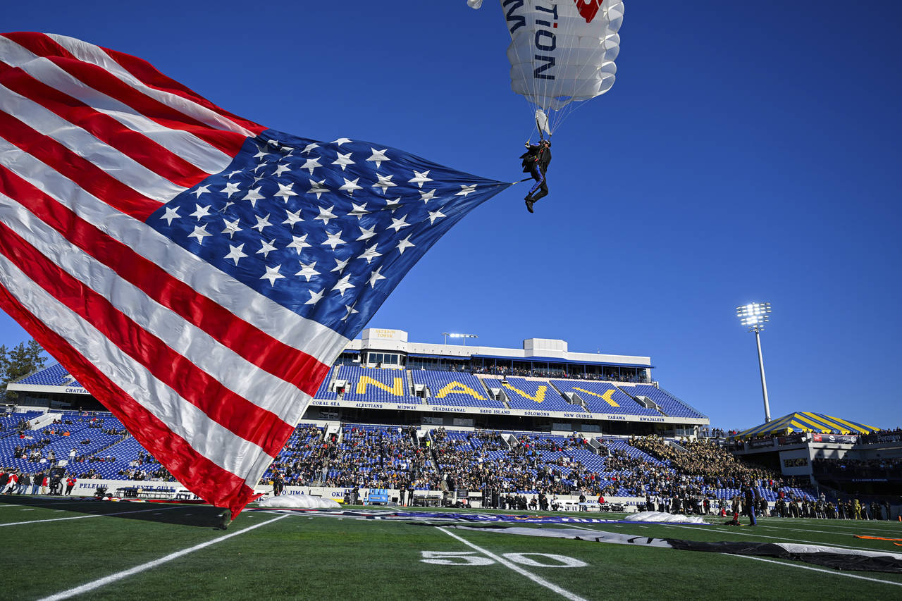 A member of Team Fastrax Parachute Jump Team lands on the field with an American flag before the Mi...