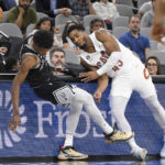 
              Cleveland Cavaliers' Donovan Mitchell, right, and San Antonio Spurs' Josh Richardson run into the scorer's table during the second half of an NBA basketball game, Monday, Dec. 12, 2022, in San Antonio. San Antonio won 112-111. (AP Photo/Darren Abate)
            