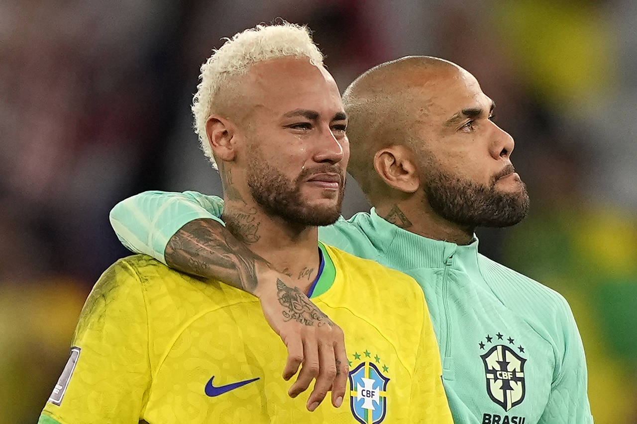 Brazil's Neymar, left, has tears in his face beside Brazil's Dani Alves, right, after losing the Wo...